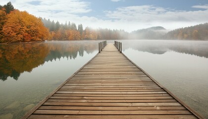 Naklejka premium Serenity in the Mist: Wooden Jetty Bridge at a Foggy Autumn Lake