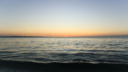 Sunset by the shore. Waves crashing into fine white sand during golden hour