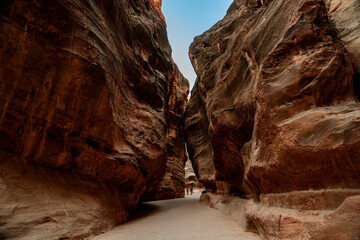 View of the narrow Siq canyon pathway leading to Petra, Jordan, with towering sandstone cliffs.