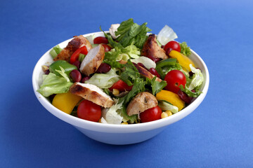 Salmon Salad with spinach, cherry tomatoes, corn salad, baby spinach, fresh mint and basil. Home made food. Concept for a tasty and healthy meal. Blue background top view. Copy space.
