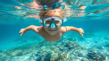 Naklejka premium A young boy, wearing a mask and snorkels, swims in the water with arms elevated