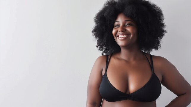 Confident plus size woman looking away with a cheerful smile while wearing underwear. Body positive woman with an Afro hairstyle, natural body and curly hair. body positive banner with copy space