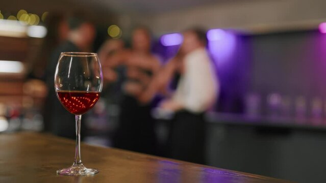 Close-up of cocktail drink in club. Banquet table with glass of alcohol cocktail on party background with silhouettes of people dancing on the dance floor. Party, event, have fun, clubbing concept.
