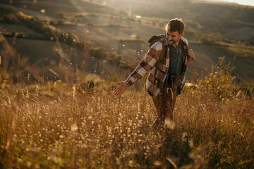 Solo hiker trekking through the sunlit golden landscape with his backpack