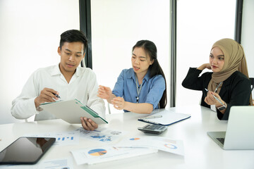 Group of Asian business people planning a project, discussing work documents.