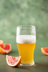 Boozy Refresing Cold Grapefruit Beer in a Pint Glass and Bottle on table. Copy space