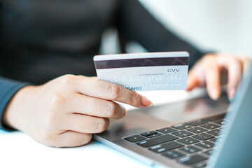 Asia woman hand holding mock-up credit card, spending online shopping with laptop at home office