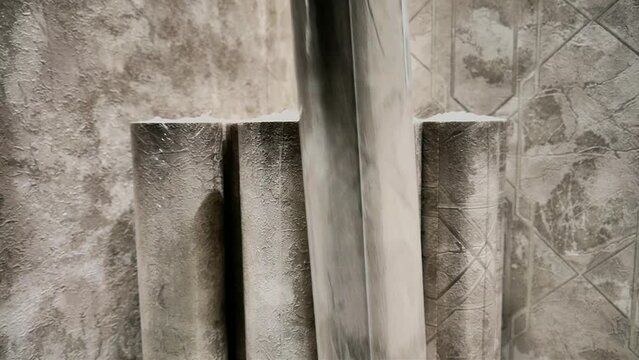 A man puts a beautiful roll of wallpaper among many others of the same kind close-up