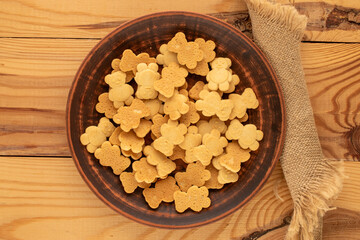 Delicious cookies in the shape of a bear in a ceramic plate on a wooden table, top view, macro.