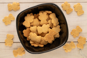 Delicious cookies in the shape of a bear in a ceramic plate on a wooden table, top view, macro.