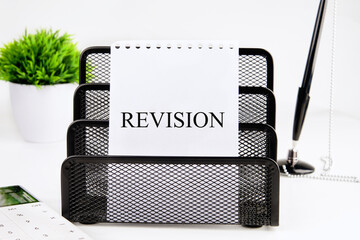 Conceptual revision symbol. REVISION word written on a blank sheet in a black stand on a white...