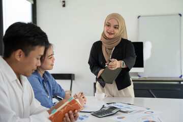 Group of Asian business men and women sitting and looking at documents at the office.