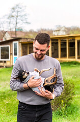 young man holding and carrying his dog terrier outdoors © Tatiana