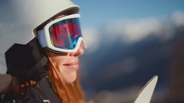 Close-up portrait of woman snowboarder skyer in ski helmet and glasses in mountains outdoors. Girl wearing in ski clothes in winter resort. Enjoy healthy sport active rest, snowboarding lifestyle.