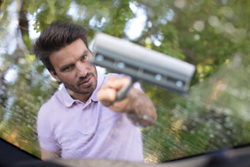 man cleaning a windshield with a squeegee
