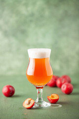 Boozy Refresing Cold Hard Plum Cider or Fruit Plum Beer in a Pint Glass on wooden table. Copy space