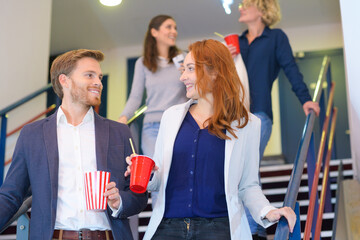 couple descending stairs in cinema holding refreshments