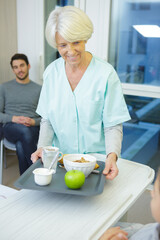 senior nurse holding breakfast tray for kid
