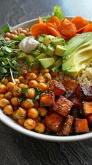 A bowl of food with a variety of ingredients including carrots, avocado, and chickpeas. The bowl is white and placed on a dark surface
