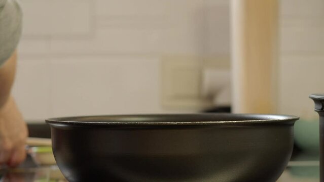 Adding crushed tomato to the sauce in the pan.