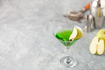 Alcoholic cocktail apple martini or green sour appletini in martini glass . Bar tools.