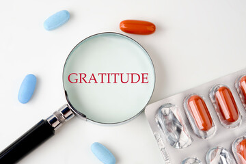 GRATITUDE Writing through a magnifying glass next to the pills - Powered by Adobe