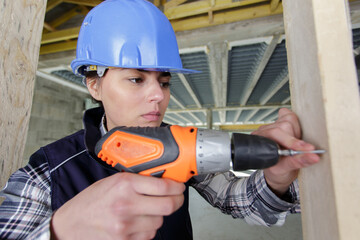 serious woman worker drills wood