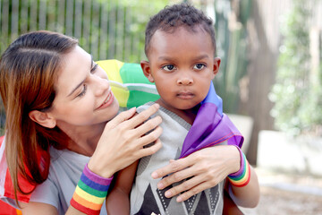 Happy homosexual lesbian woman and her adopted child with rainbow flag. Young beautiful girl and...