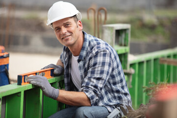 male builder on construction site using a spirit level