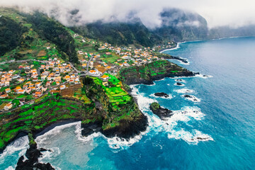 Aerial view of rough ocean with waves, volcanic beach and swiming pool in Seixal, Madeira, Portugal