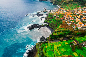 Aerial view of rough ocean with waves, volcanic beach and swiming pool in Seixal, Madeira, Portugal