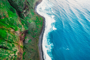 Aerial view of rough blue ocean with waves, volcanic beach in Teleférico das Achadas da Cruz, Madeira, Portugal