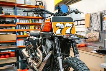 Close up of black and red custom motorbike on empty workshop. Vintage scrambler motorcycle in...