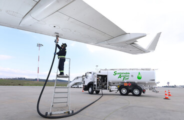Technician is refueling aircraft with Sustainable Aviation Fuel (SAF) at the airport.