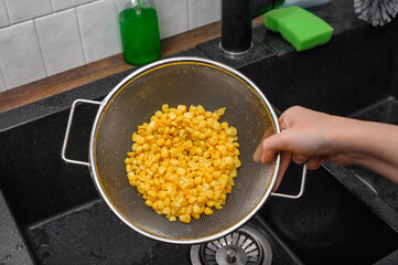 Żółta słodka kukurydza z puszki, chrupiące ziarna na sitku kuchennym z bliska 