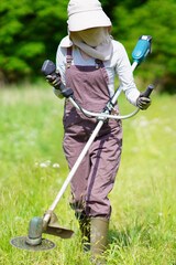 電動草刈り機で草刈りをする女性