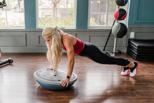 Woman doing planks on balance trainer in gym