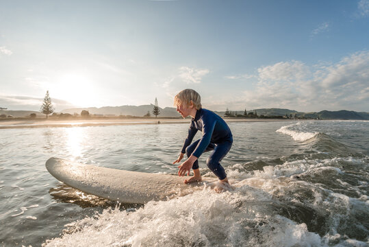 Child surfing at sunset in New Zealand