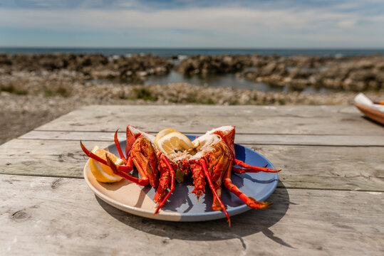 Plate of fresh rock lobster crayfish on table next to ocean