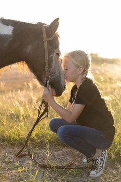 Girl with braids kissing pony