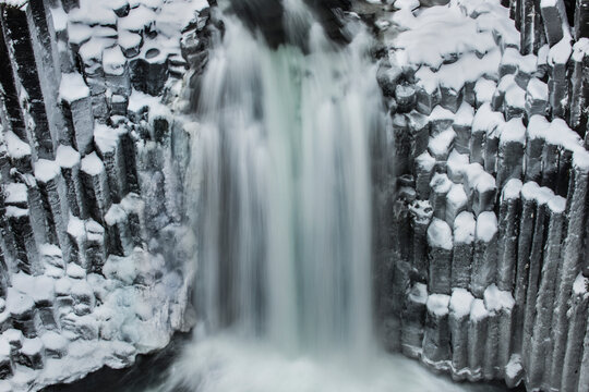 A massive waterfall called Litlanesfoss surrounded in columnar b