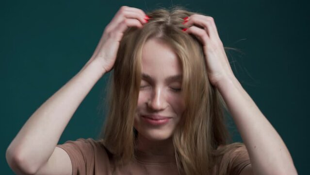 young woman experiences an itchy scalp due to scalp fungus, dandruff and a red rash. She scratches her head for relief. Consultation with a doctor is necessary due to problems with hair and hair loss
