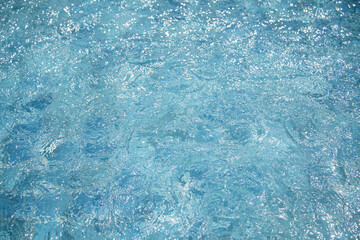 blue water of swimming pool with sun light and ripples background