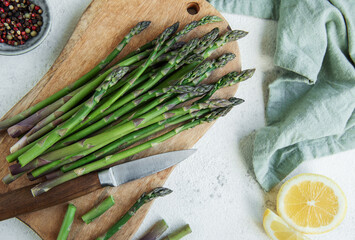 Fresh Asparagus Spears on a Wooden Cutting Board With Lemon and Chefs Knife © Olena Rudo