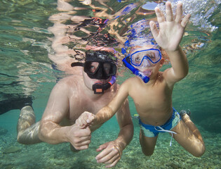 A father teaches his son to snorkel.
