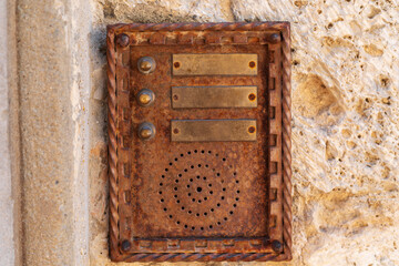 close up of an old rusty intercom embedded in weathered stone wall, blending technology with traditional architecture
