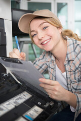 happy young female technician working on photocopier