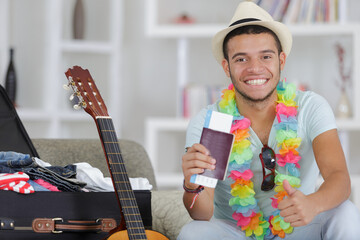man preparing his suitacse holding passport with thumbs up
