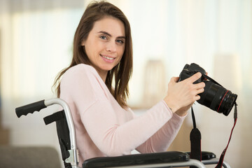 woman in wheelchair at home holding dslr camera