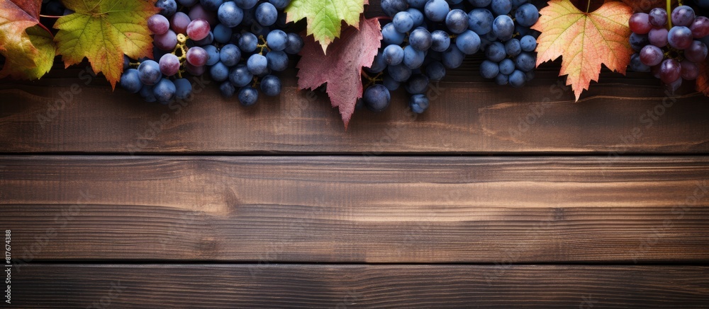 Poster A top down view of blue grapes and vibrant grape leaves on weathered wooden table creating a captivating background for copy space image